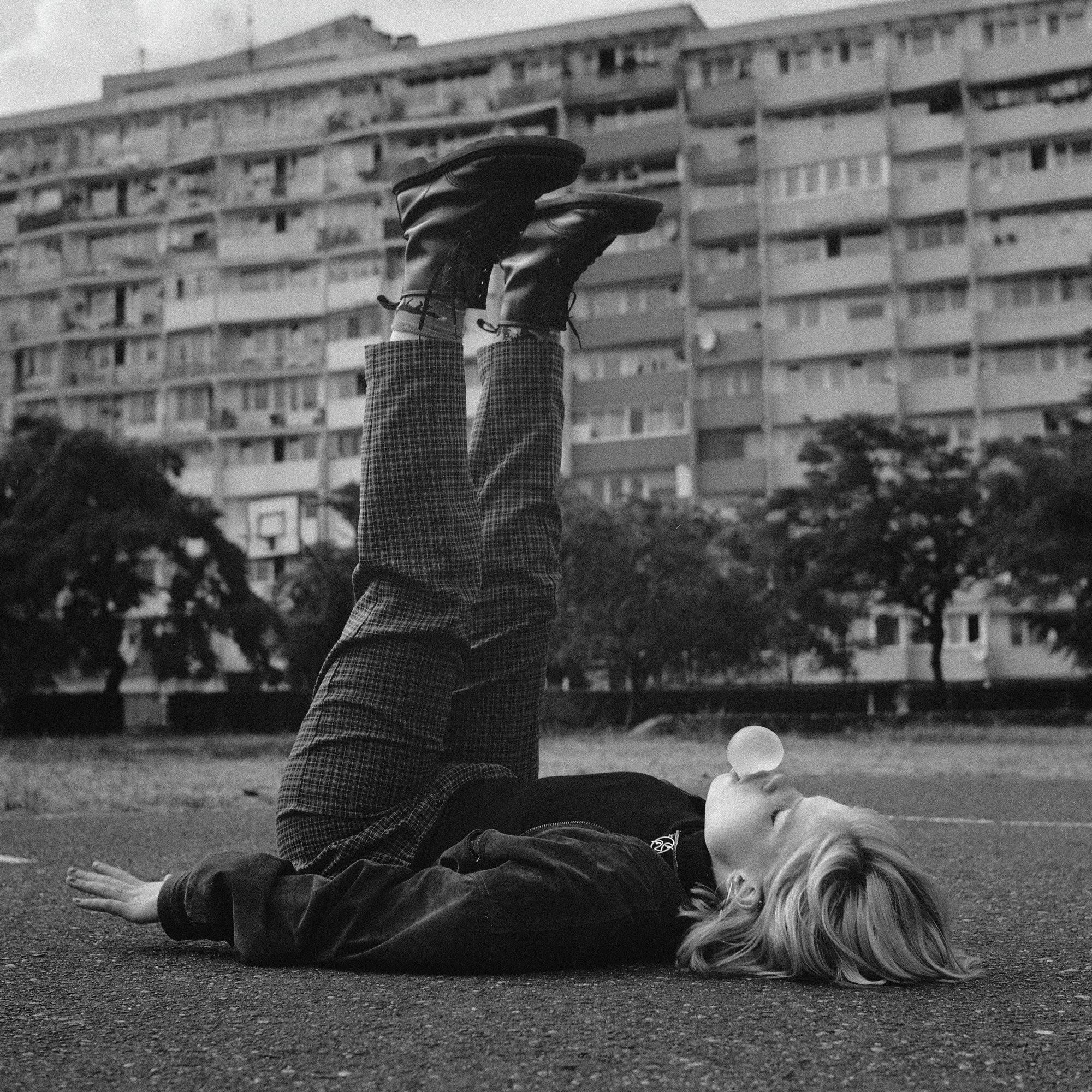 Czarno-biała fotografia analogowa osoby leżącej na trawie